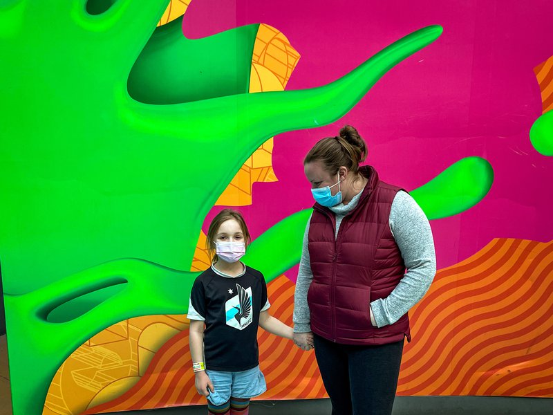A mom and her young daughter stand in front of a colorful wall, while exploring Nickelodeon Universe at Mall of America.