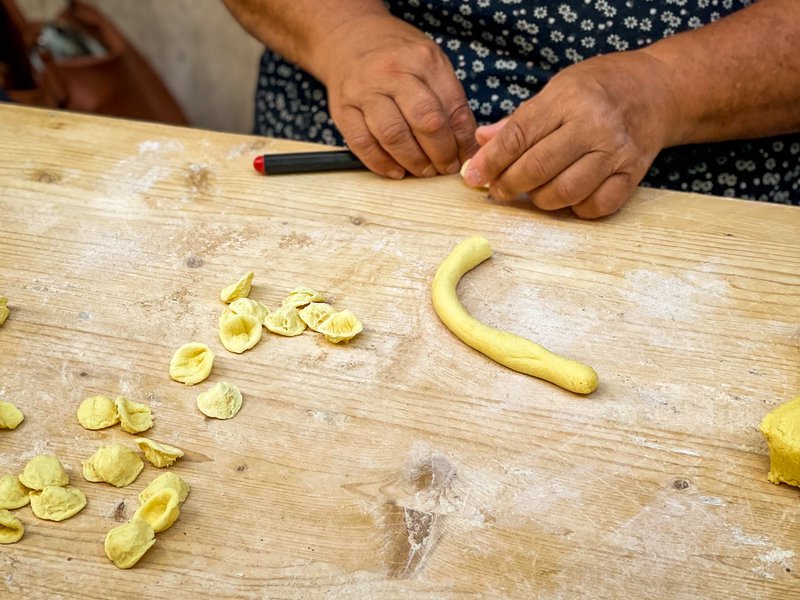 A woman&#x27;s hands make pasta on a street in Bari.