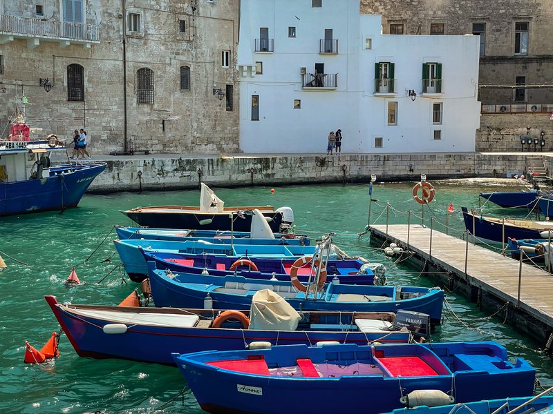 Several boats float in the water of the old port in Monopoli.